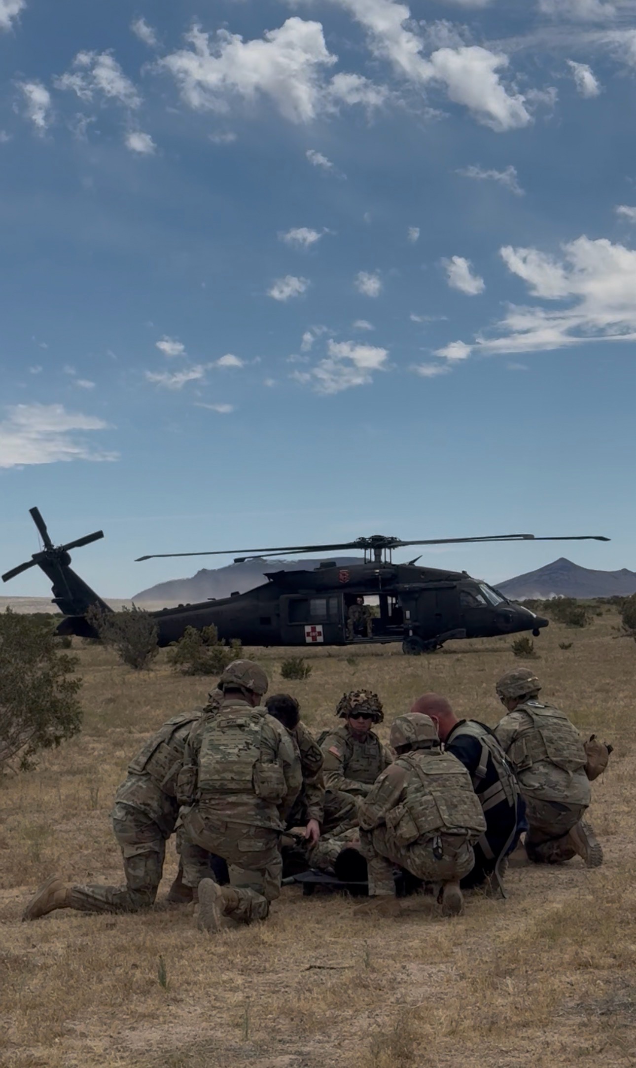 Soldiers training around a medical evacuation helicopter during a field exercise